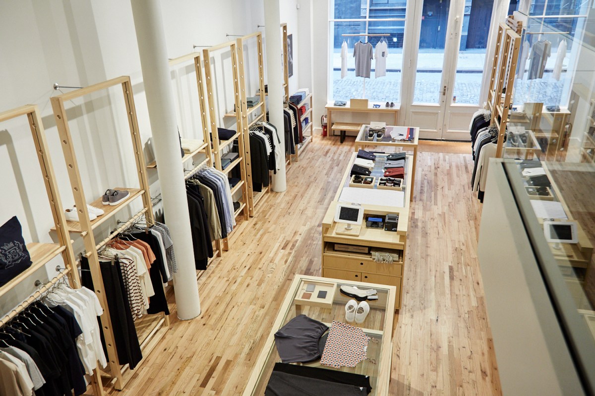 clothes hanging and clothes folded in center, wooden floors, window facing street