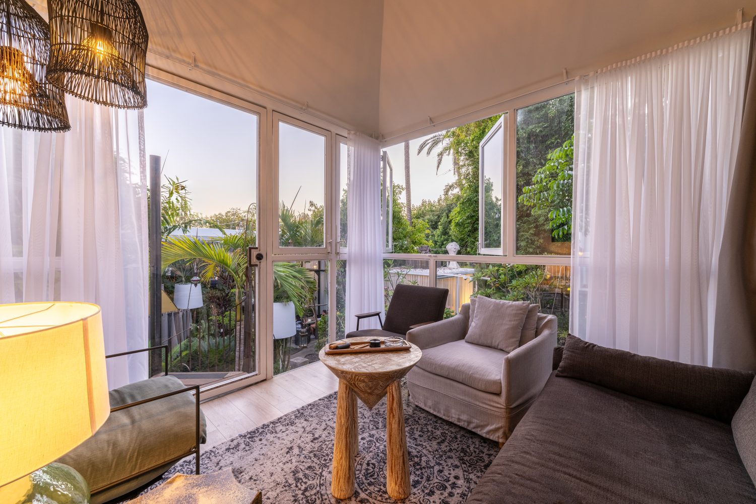 sofa and chairs, open windows facing palm trees, white curtains, lamps