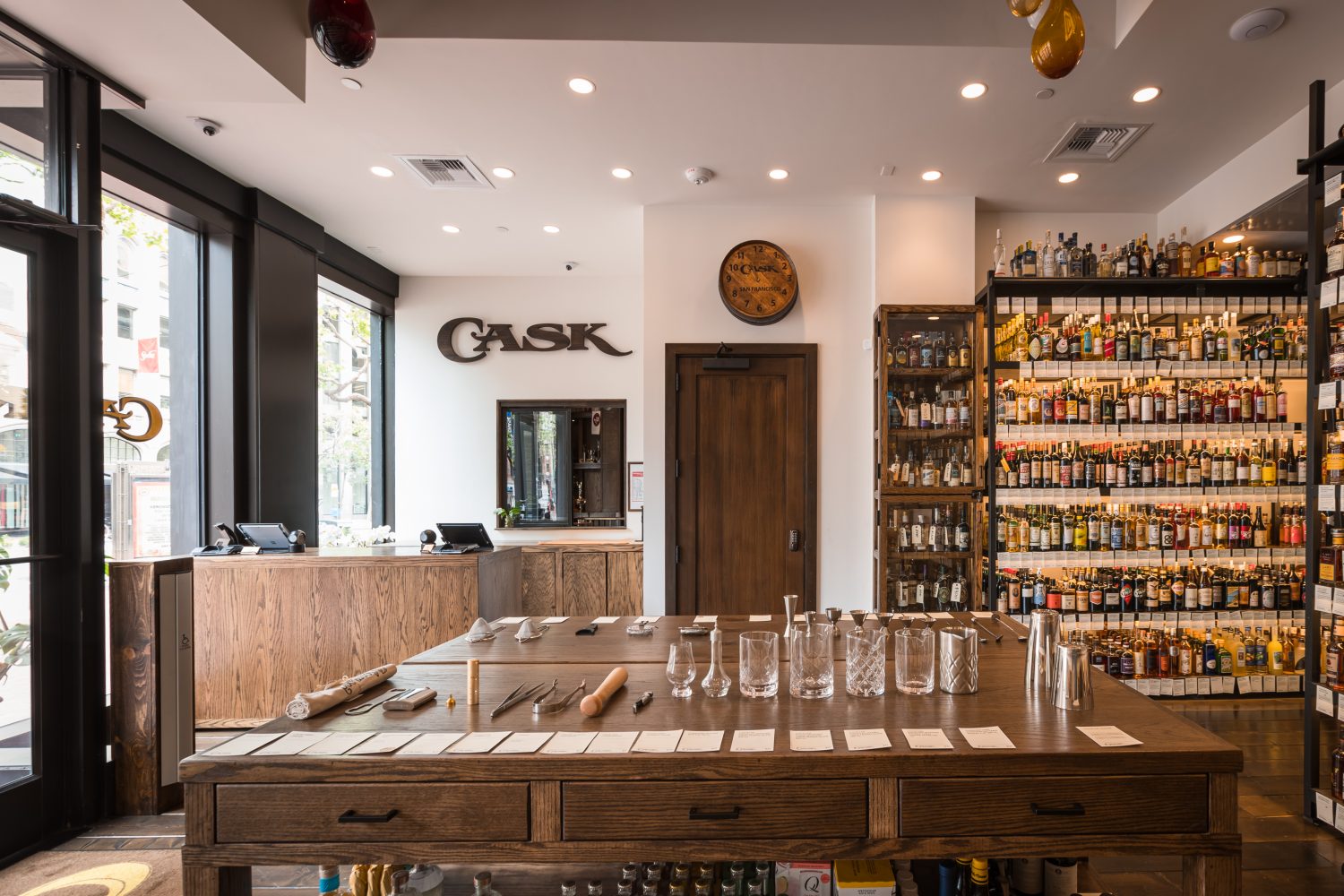 bottles of liquor on shelves, glasses and tools on table