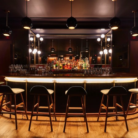 Bar area at Allegory, with round bar and bottles behind it