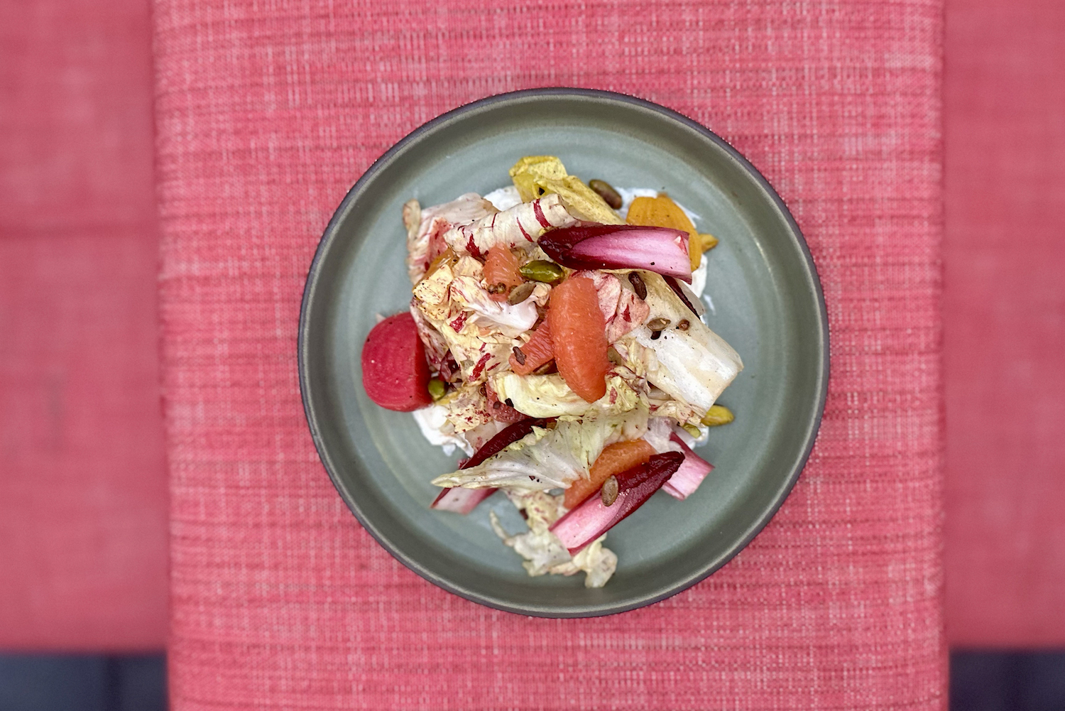 a plate of beets and lettuces on a red tablecloth