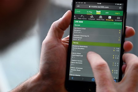 A man's thumb hovering over a mobile betting app. Here's what online gambling is doing to our brains and bodies.