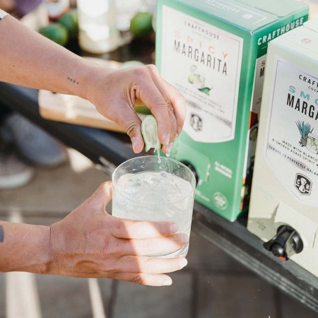 A person (off-camera) squeezing a lime over a margarita from Crafthouse Cocktails. The brand is one of several that's launched a "boxed cocktail" line, which makes it easier (and cheaper) to serve cocktails in a large-format setting