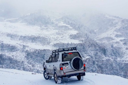 A car driving through snow on a mountain.