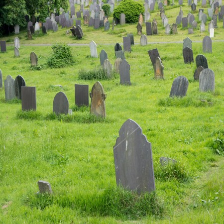 A cemetery with flush green grass surrounding the tombstones.