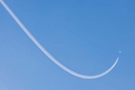 An airplane flying with a contrail being produced behind it