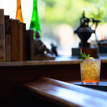 Whiskey glass on a table in front of row of books