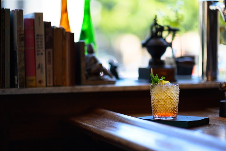 Whiskey glass on a table in front of row of books