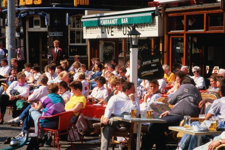 Dozens of people sitting close together at a cafe. Next time you're out and about, keep your headphones in your pocket and practice eavesdropping. It's good for you.