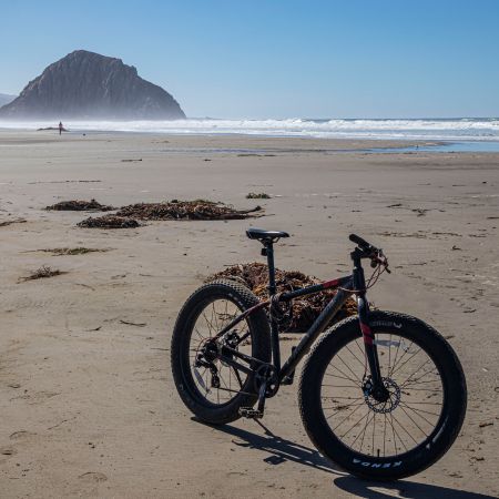 A fat tire bike parked on a beach in California.