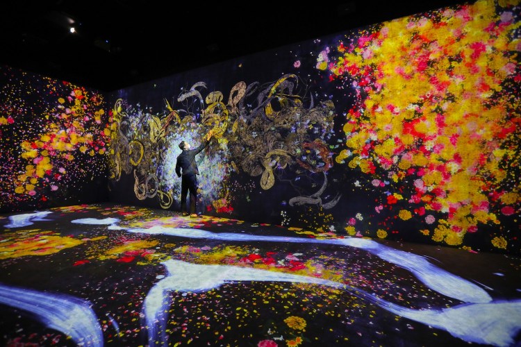 A staff member interacts with the exhibit during a media preview of the exhibition "teamLab: Continuity" at Akiko Yamazaki and Jerry Yang Pavilion of Asian Art Museum in San Francisco