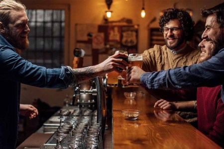 A group of friends drinking beer at a local pub and having a conversation with the bartender