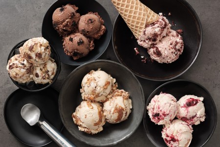 Scoops of ice cream in a bowl with a cone and an ice cream scoop from a birds-eye view