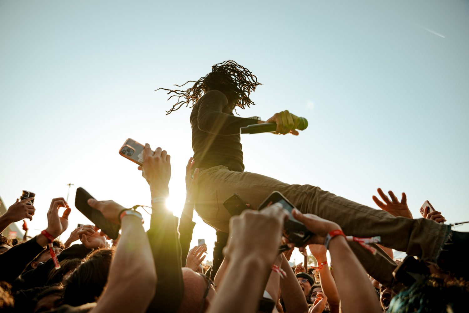 performing man with hair in the wind on top of a crowd with hands up