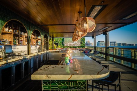 green bar area with seating on rooftop overlooking city skyline