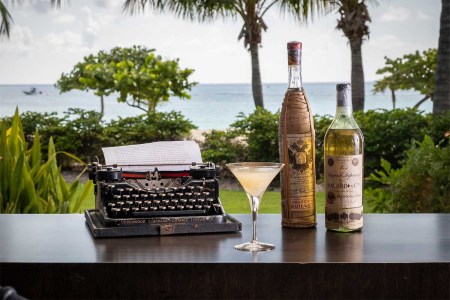 The E Hemingway Cocktail, vintage rums and a typewriter in front of Library by the Sea in Grand Cayman