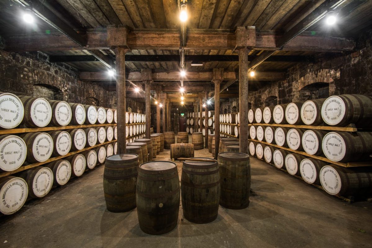 stacked wooden barrels inside a distillery