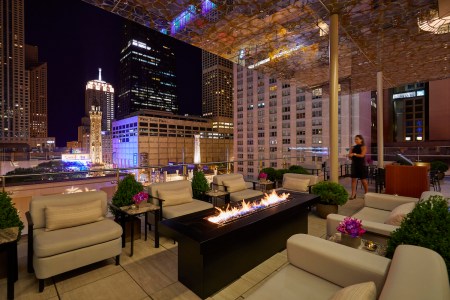 Rooftop seating area with fireplace overlooking Chicago's city skyline at the Peninsula hotel downtown