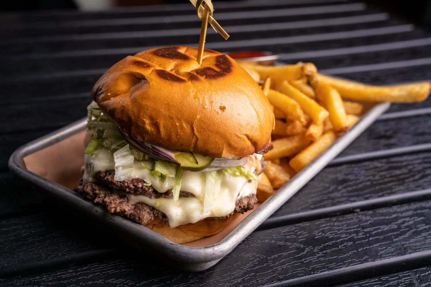 burger with double patty, lettuce, cheese, and french fries 