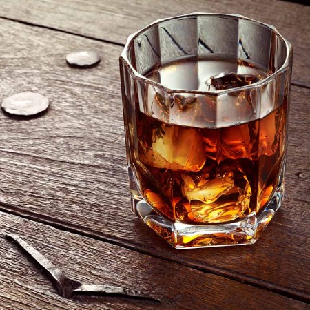 Whiskey with ice in crystal glass on wood table. Many rye whiskies take on a regional characteristic.