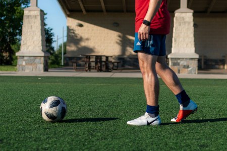 A man approaching a soccer ball on a turf field.