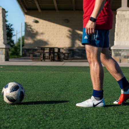 A man approaching a soccer ball on a turf field.