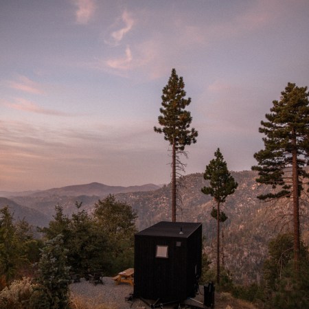 View of small black cabin overlooking mountain view