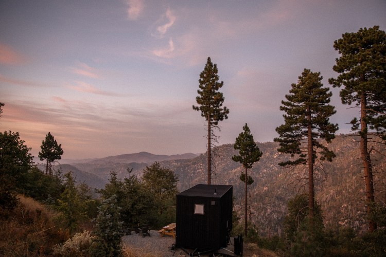 View of small black cabin overlooking mountain view