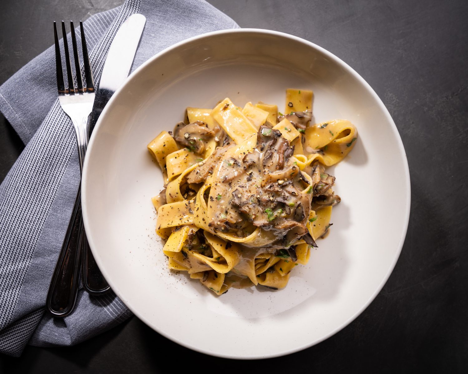 pasta with mushrooms on a plate next to silverware