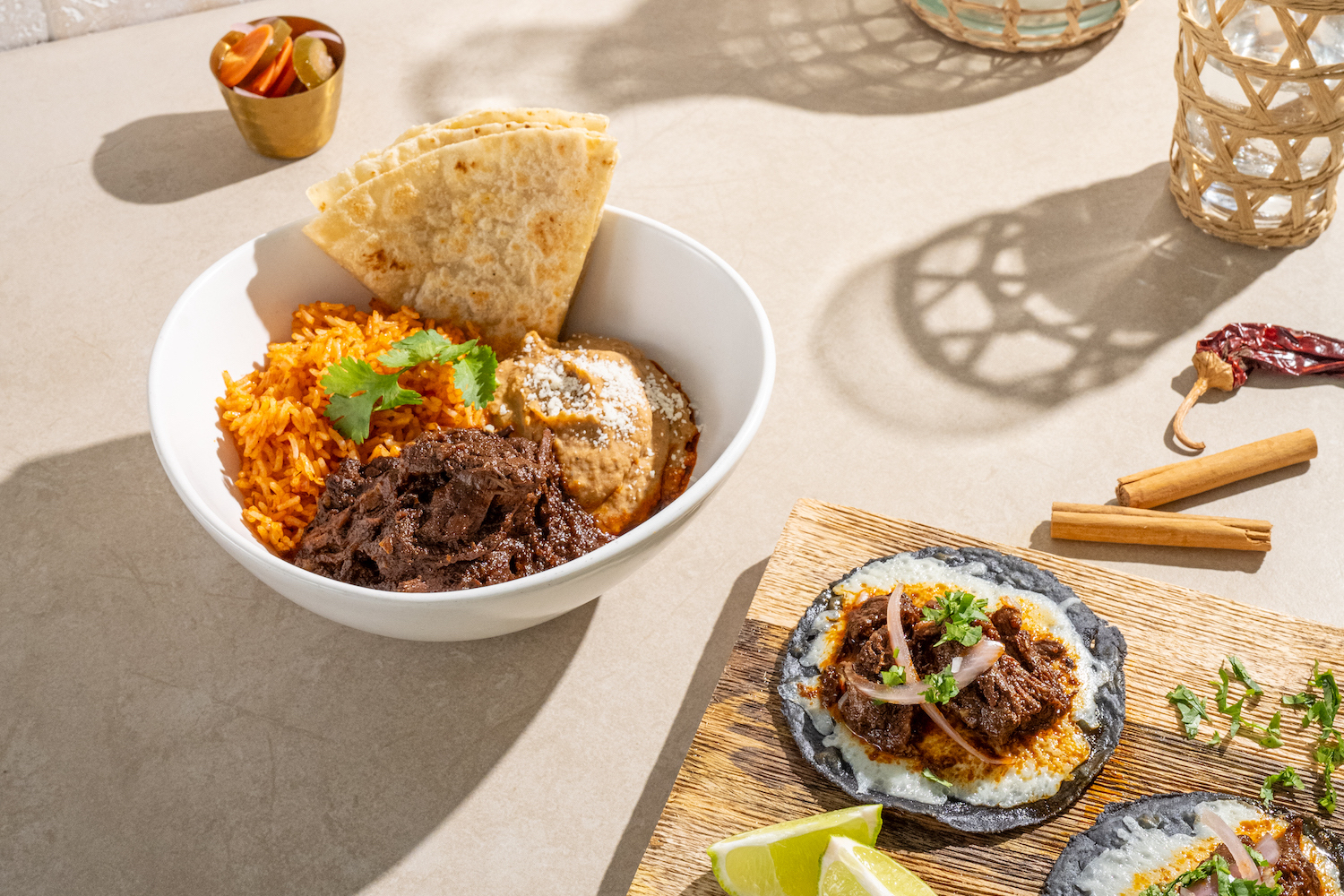 a wooden board with two tacos and burrito bowl shot in natural sunlight