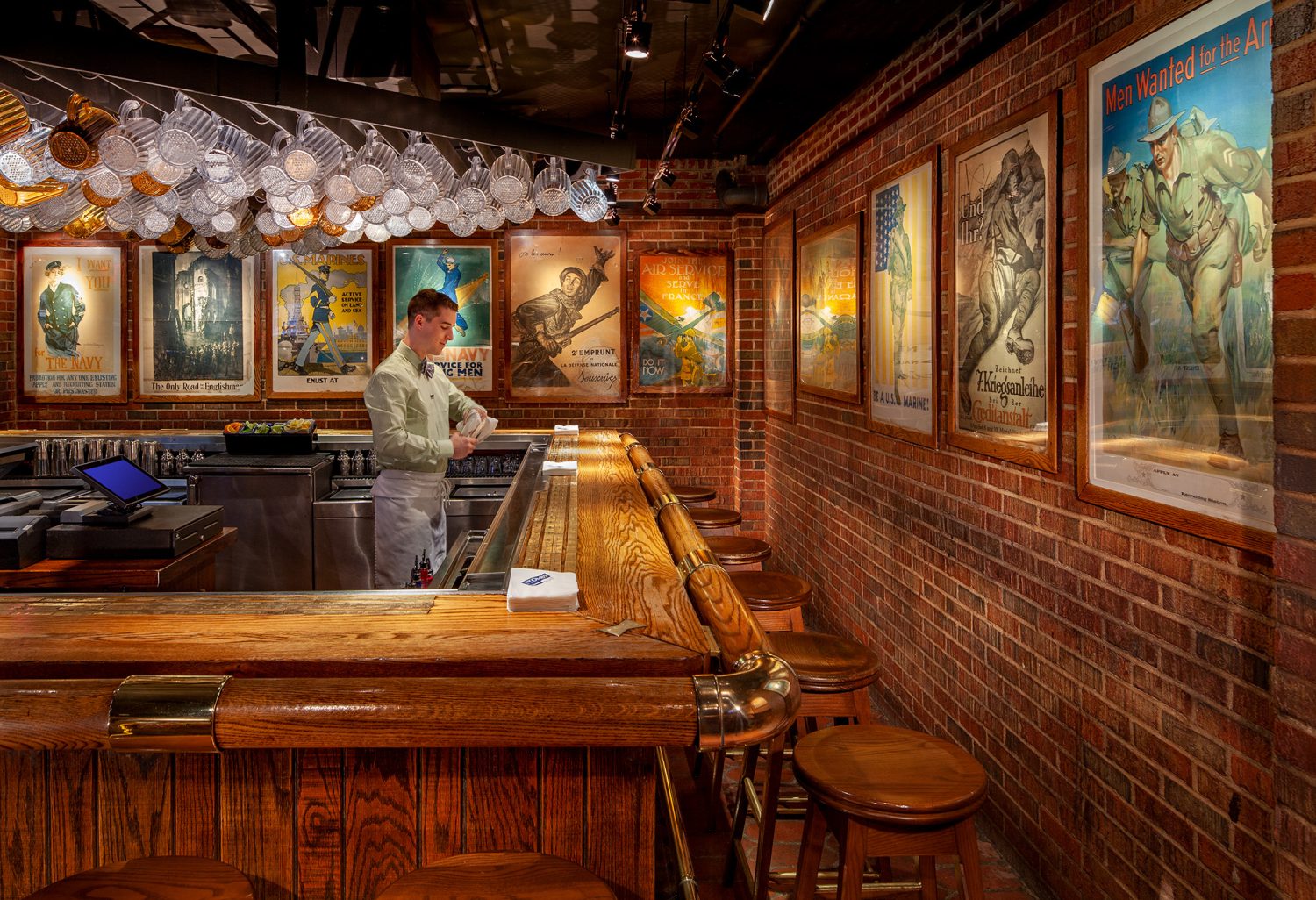 bartender cleaning glasses at bar with war posters on the wall