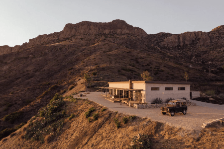 house on top of a large mountain with sunlight hitting it