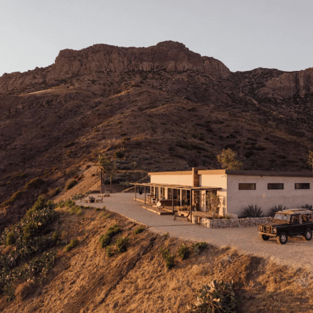 house on top of a large mountain with sunlight hitting it