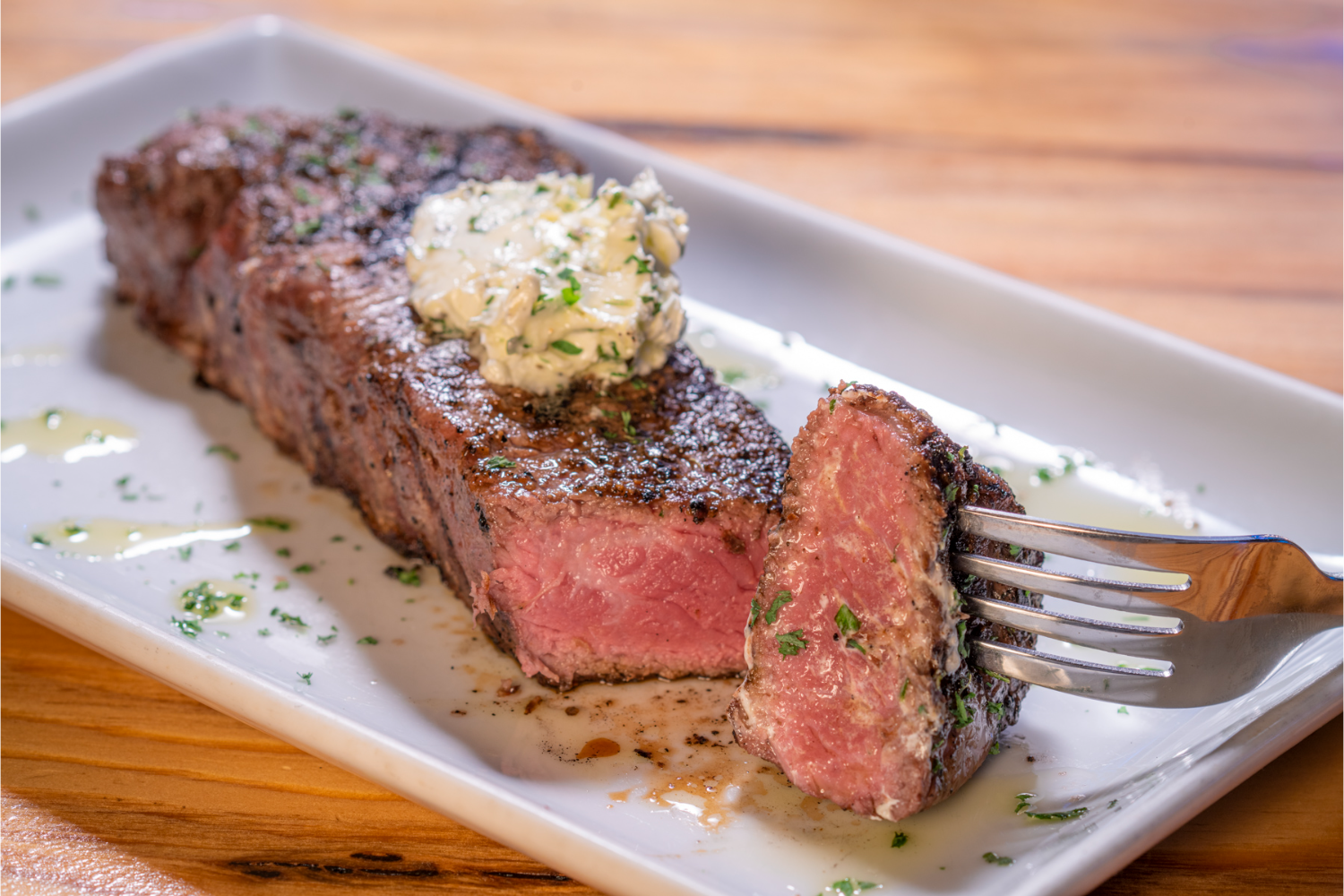 steak cut with a piece on a fork, creamy sauce on top