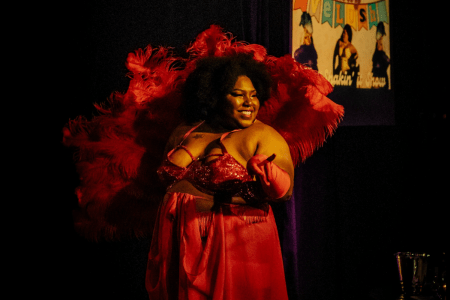 women in red dress and red feather boa behind her