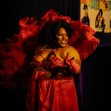 women in red dress and red feather boa behind her