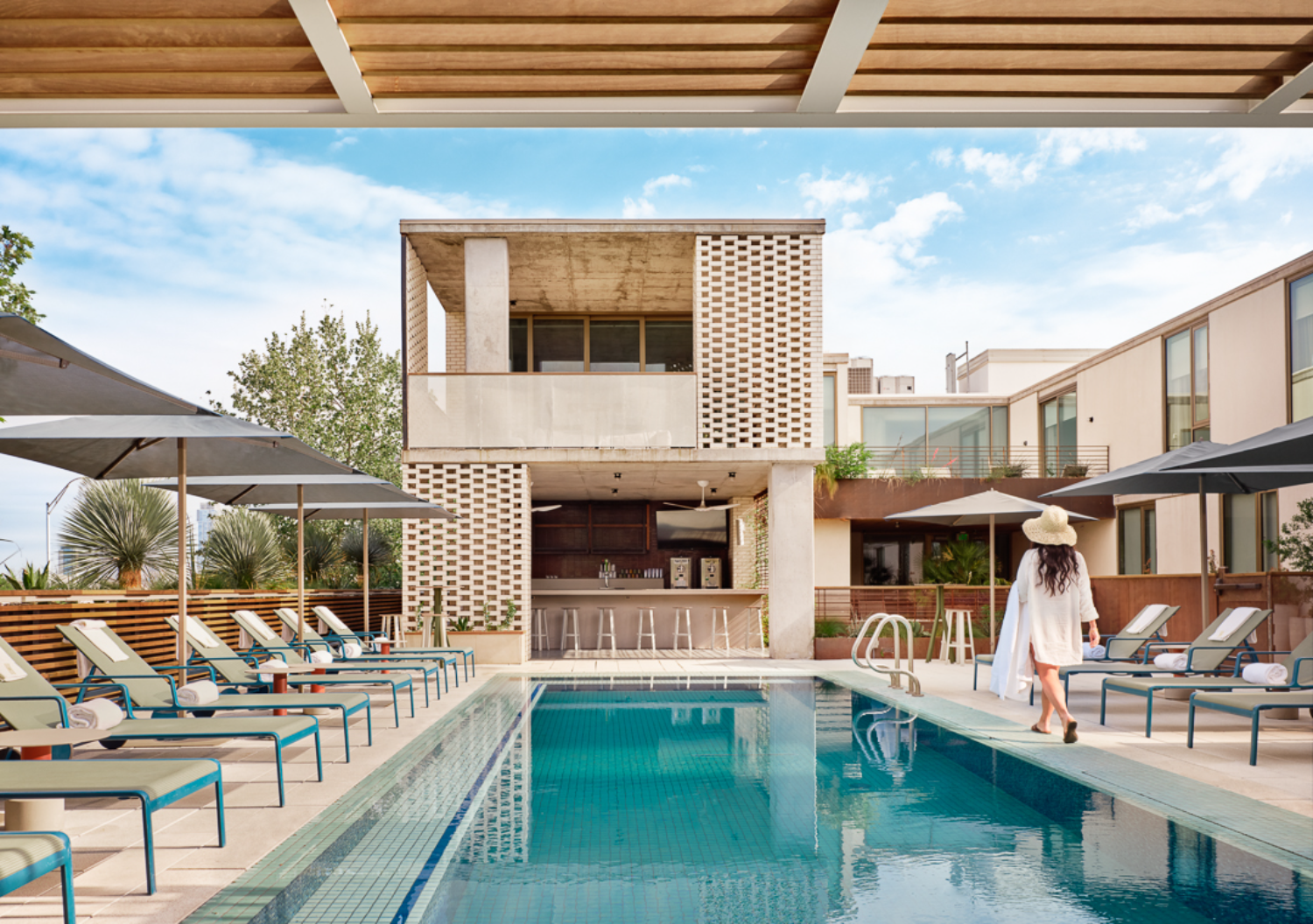 pool with chairs and woman walking in white clothes and hat